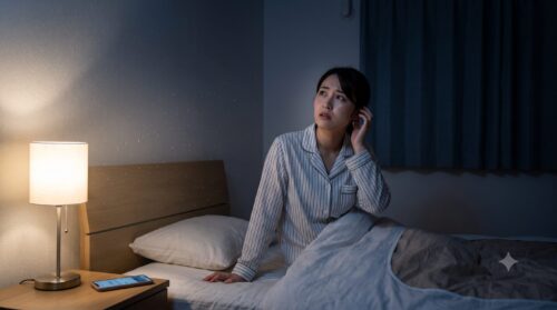 夜中に天井裏から聞こえる不気味な物音に怯え、布団の中でスマートフォンを使いネズミ駆除業者を検索する日本人女性の様子。